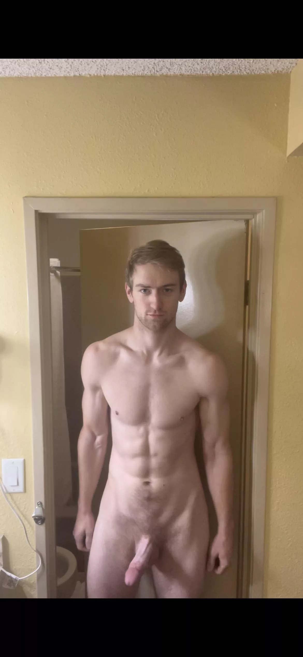 Large man erect outside hotel bathroom.