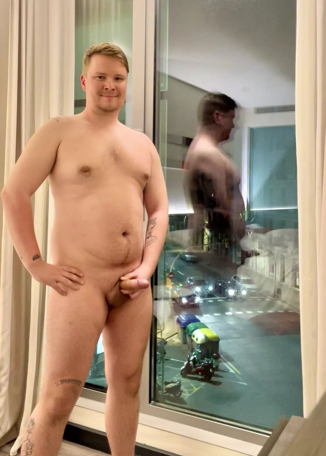 Night time, busy street, big window, lights on, happy exhibitionist