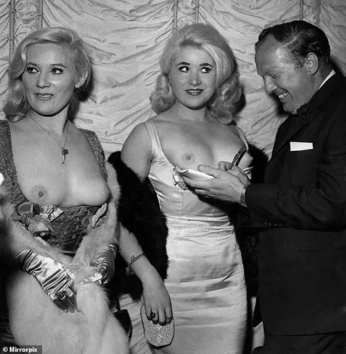 August 1964 : Marion and Valerie Mitchell attend a movie premiere in London, wearing topless dresses.  Marion later went by the name 'Janie Jones' when she became a singer.  In the mid 1960's there was a brief fashion craze for the 'topless dress', 