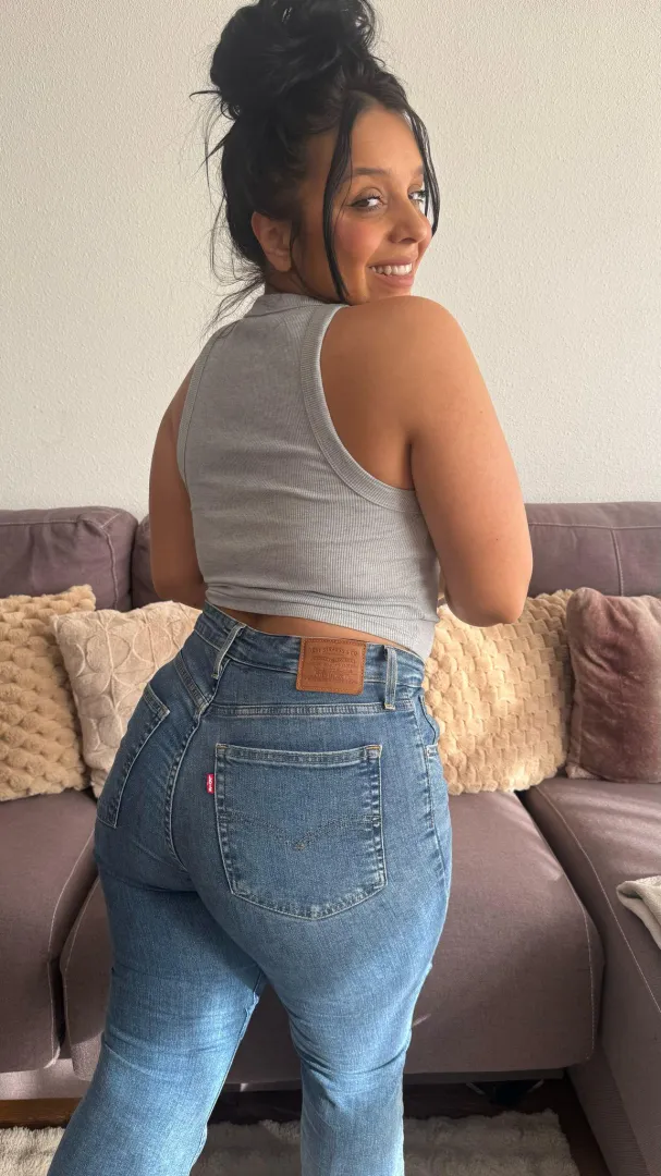 Bronzed curves in snug denim igniting sassy warmth ruling the shore with fiery allure