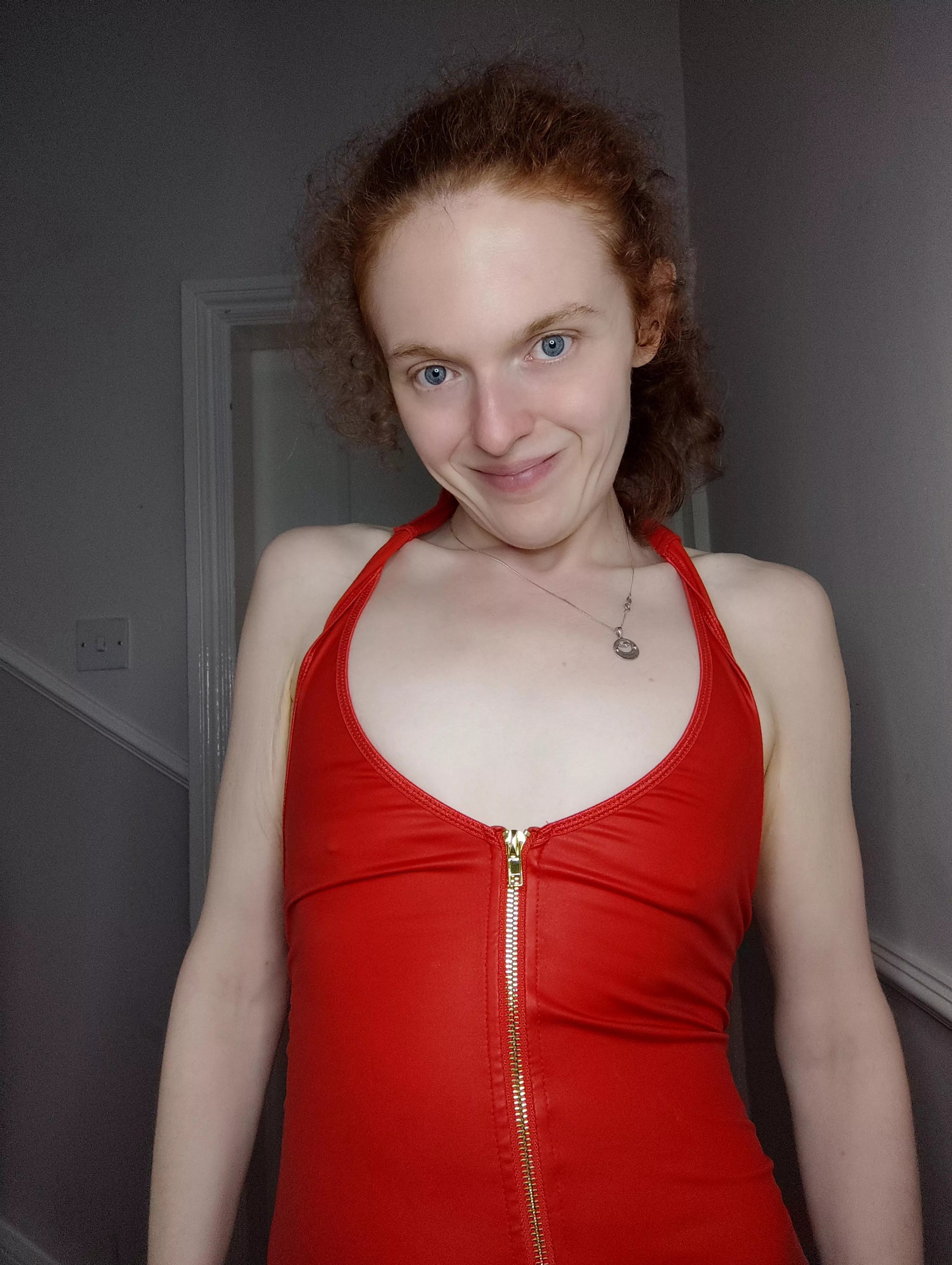 A redhead who is braless in a red dress