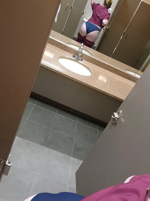 Naughty nurse in public bathroom apparently with a wedgie.