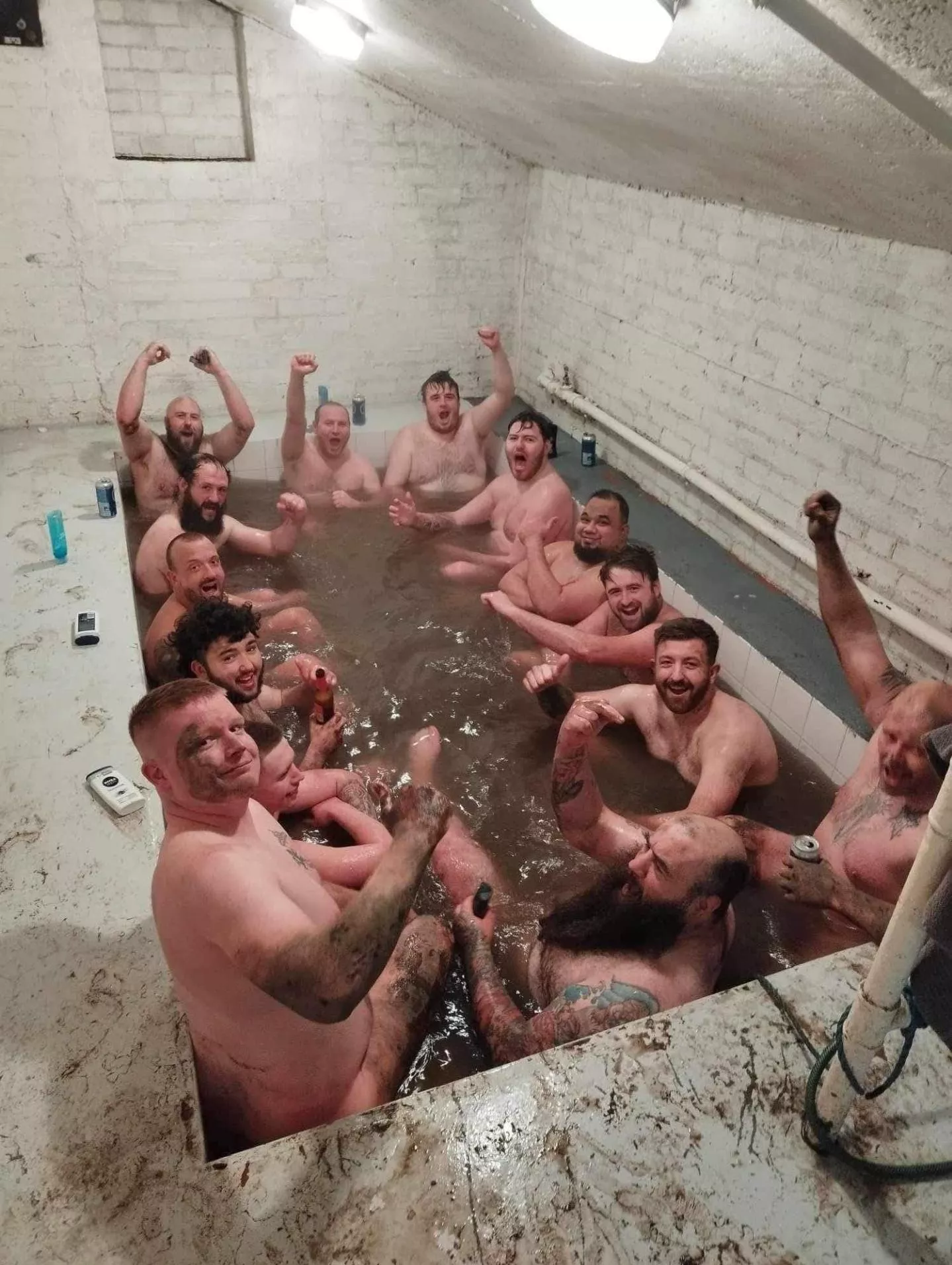 British rugby team sharing a bath and beers together after a match.