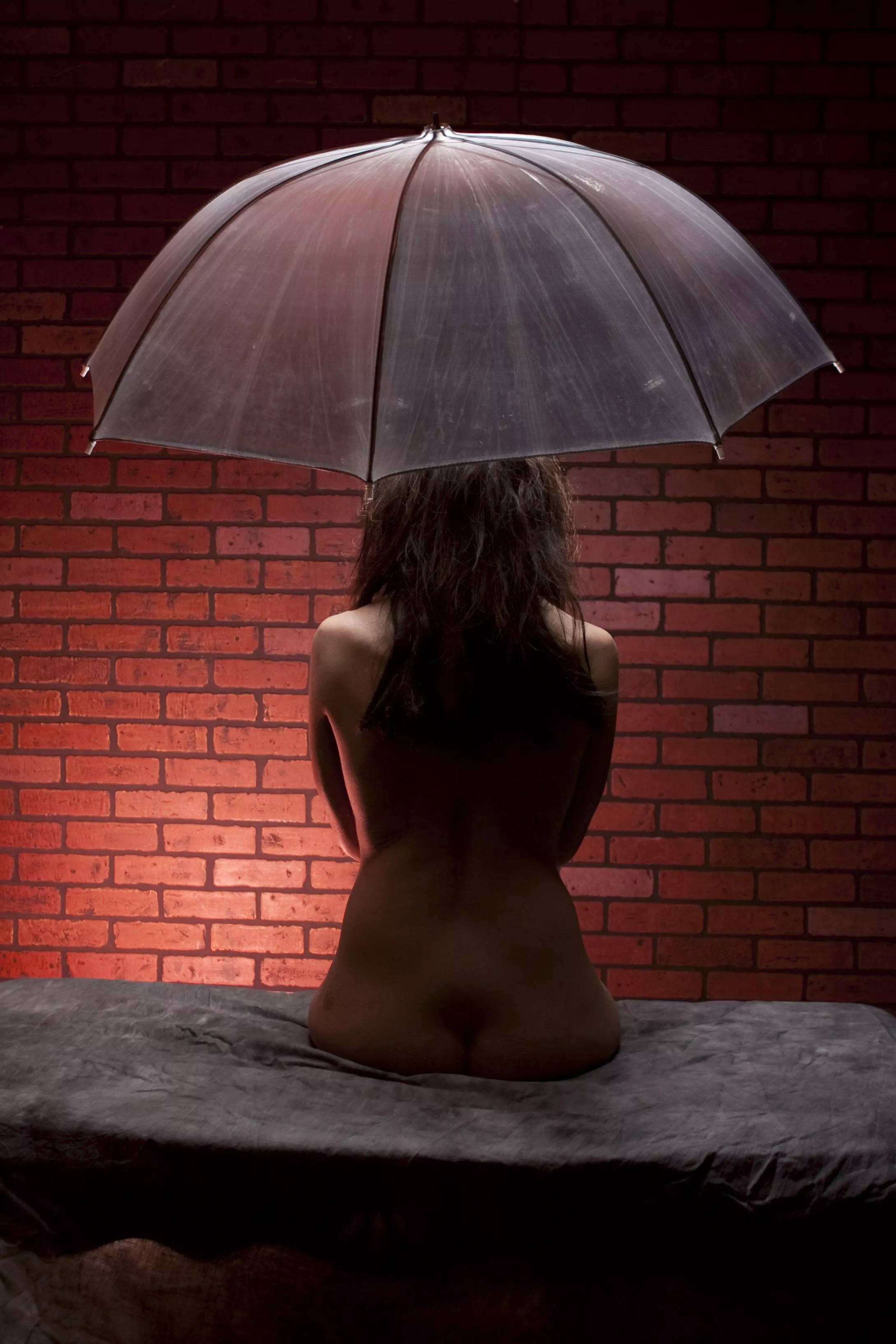 Brunette, waiting in the dark in front of the brick wall. 