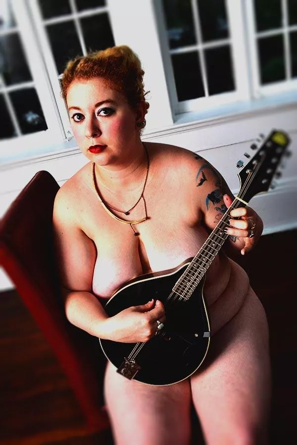 I think she is playing a banjo. Quite shy b.t.w. (or am I reading her facial expressions not right?)