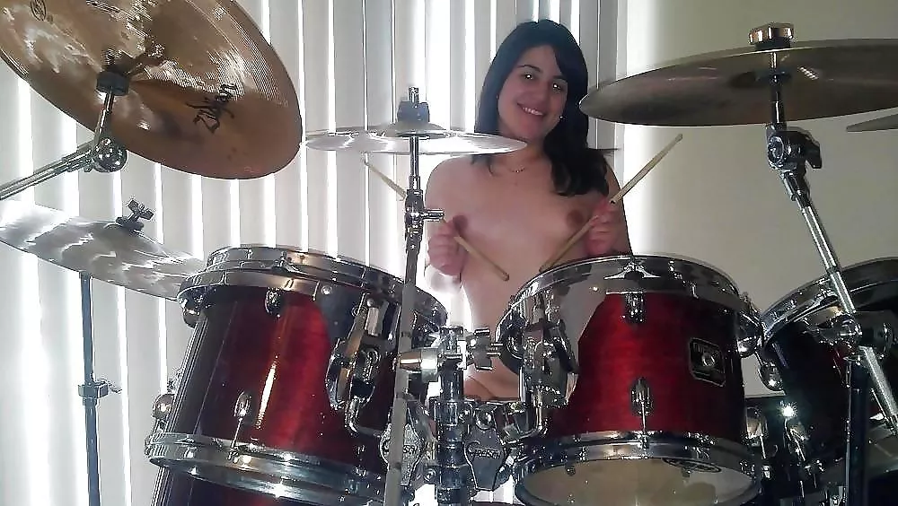 Cheerful amateur drummer girl (who is holding the sticks incorrectly)