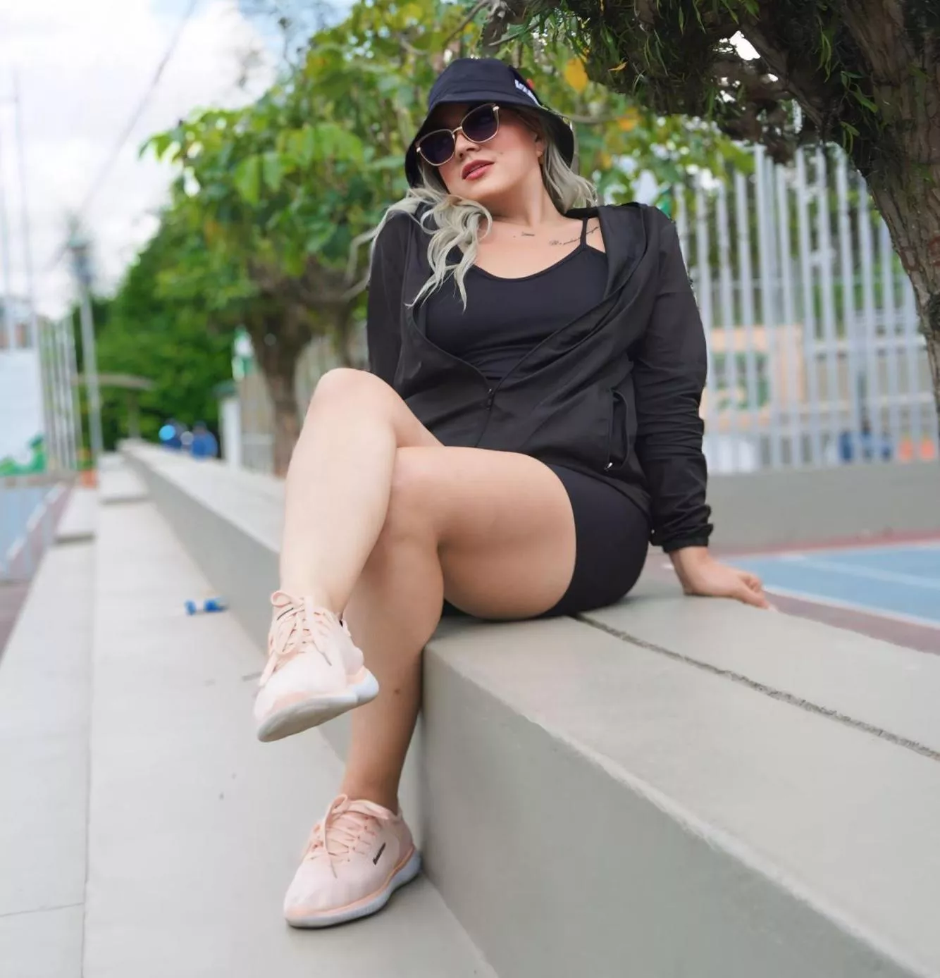 This stunning blonde in a black outfit and stylish hat flaunts her curves with confidence