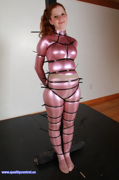 One of the best shot from QCCP ever to me: Cynthia is ziptied to a pole, wearing a pink and shiny catsuit