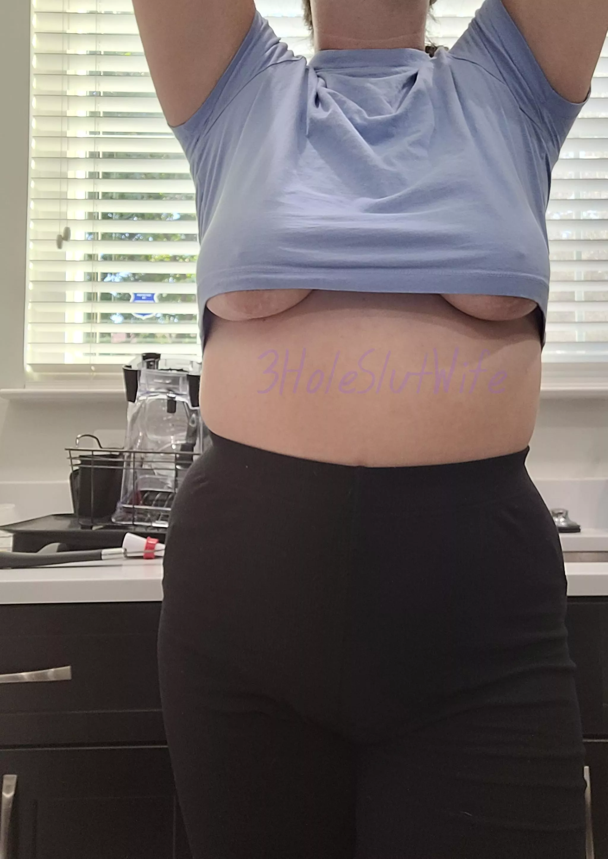 Underboob pops out reaching for the top shelf